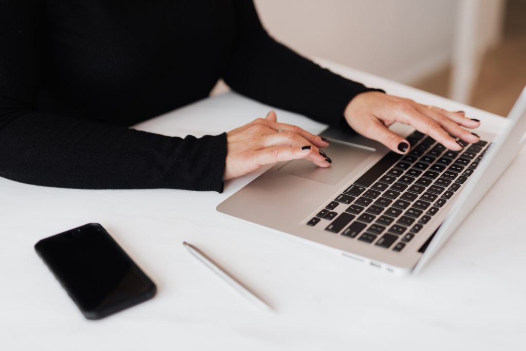 person using laptop on table to take meeting minutes