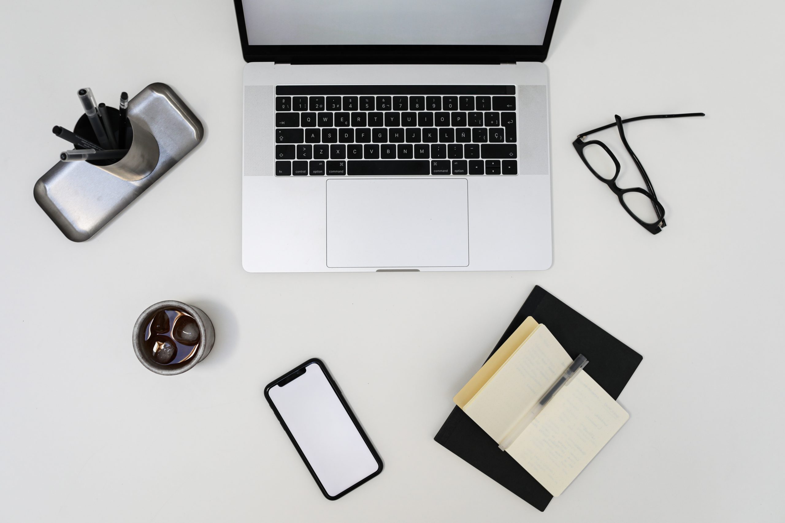 laptop notebook phone glasses spread out on white table